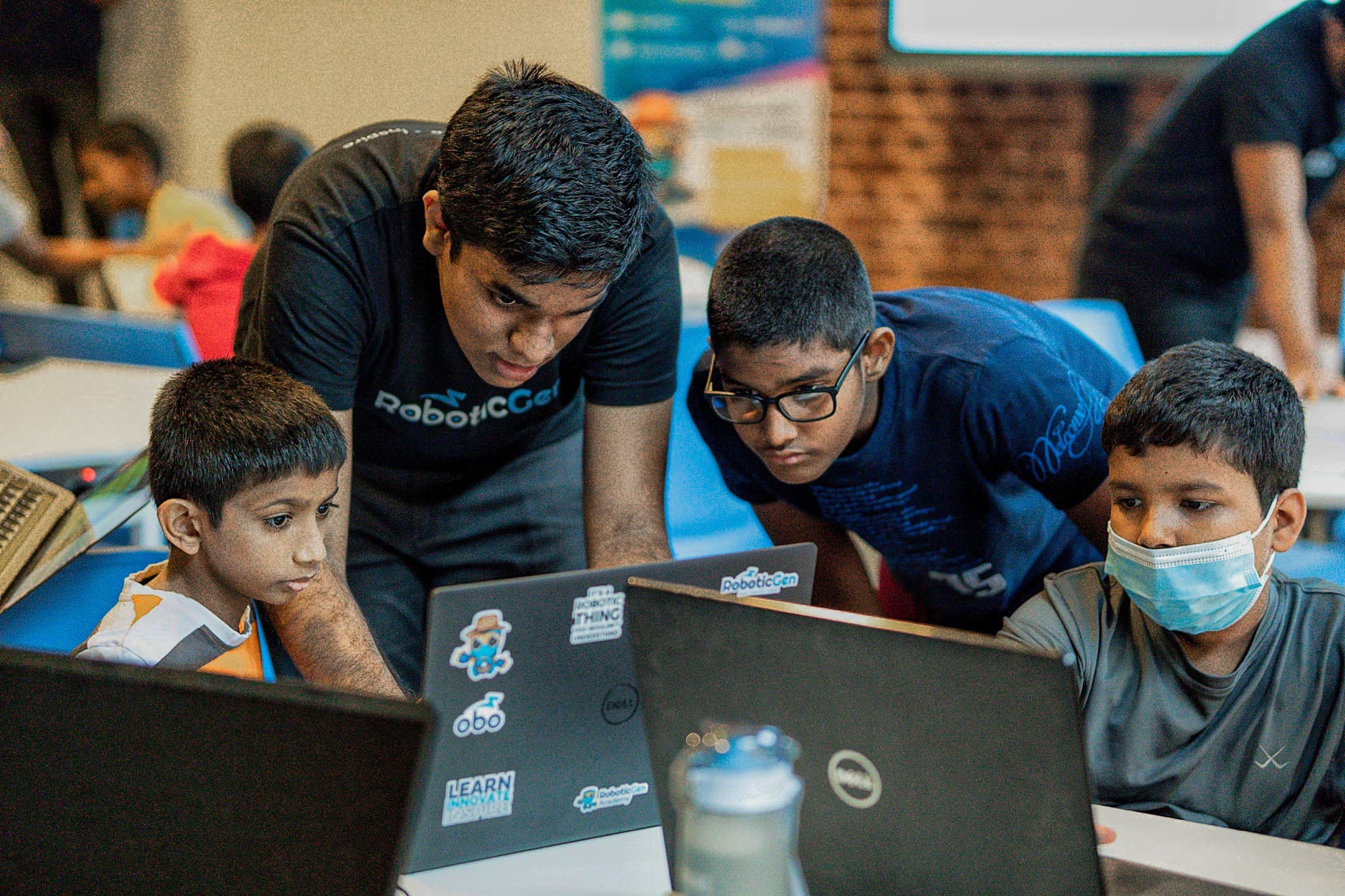 Mentor helping kids with laptops